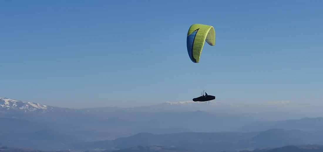 Green Niviuk Peak 4 flying above snow-capped peaks